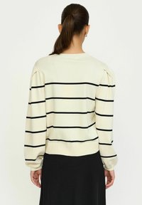 Maglione crema con strisce orizzontali nere, bordo e polsini a coste e spalle puffate. Morbida texture a maglia, design casual.