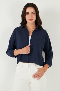 Navy blue cropped shirt with a collar, button closure, and a front chest pocket. Smooth texture and long sleeves rolled up at the cuffs.