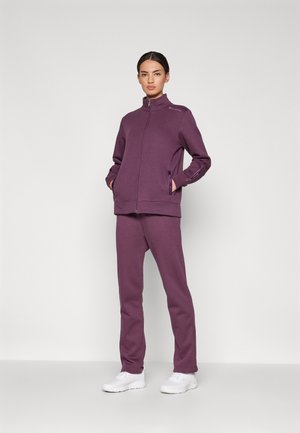 Sudadera morada con cremallera y cuello alto, combinada con pantalones de chándal morados a juego. Ambos están hechos de una tela suave, con costuras de acento y bolsillos.