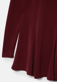 Robe rouge foncé à manches longues, évasée, avec ourlet cousu et détails de coutures verticales sur tissu doux.