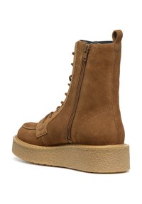 Stivale alla caviglia in suede marrone con suola piatta e testurizzata. Presenta una chiusura con cerniera e un design con lacci. Punta arrotondata e dettagli di cucitura rinforzati.