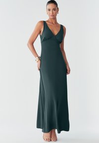 Pikk, tumeroheline varrukateta kleit V-kaelusega, istuva ülakeha ja voolava seelikuga. Sile kangas õrnade volditamisdetailidega.