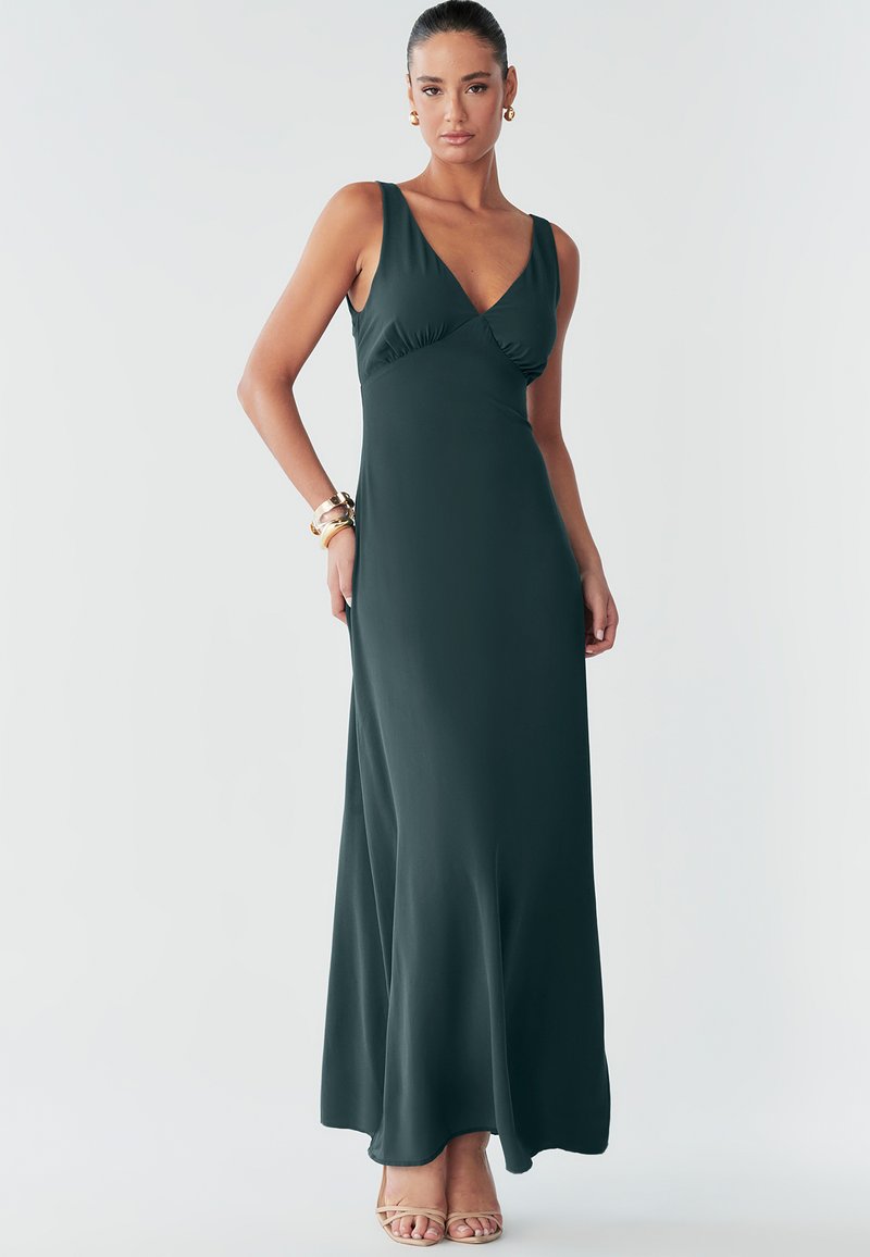 Pikk, tumeroheline varrukateta kleit V-kaelusega, istuva ülakeha ja voolava seelikuga. Sile kangas õrnade volditamisdetailidega.