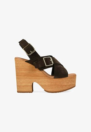 Sandalia de plataforma de ante marrón oscuro con tacón alto grueso de madera y dos correas ajustables con hebilla cruzando el pie y el tobillo.