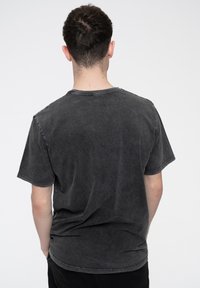 Gray cotton t-shirt featuring a crew neck, short sleeves, and a faded, distressed texture. Seam details visible on shoulders and hem.