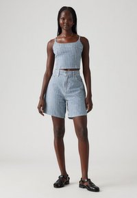 Blå och vit randig crop top och högmidjade shorts, gjorda av denim, med en åtsittande design och synliga sömmar. Svarta sandaler fulländar outfiten.