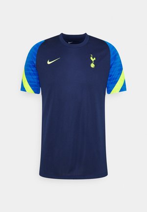 Maillot bleu marine à manches courtes de Tottenham Hotspur, avec des empiècements bleu vif et vert citron sur les manches, le swoosh Nike vert citron et l’écusson du club.