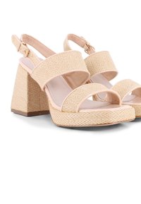 Sandalias de cuña beige con parte superior de tejido trenzado texturizado, tiras anchas, diseño de punta abierta y un tacón grueso para mayor estabilidad. Correa ajustable en el tobillo.