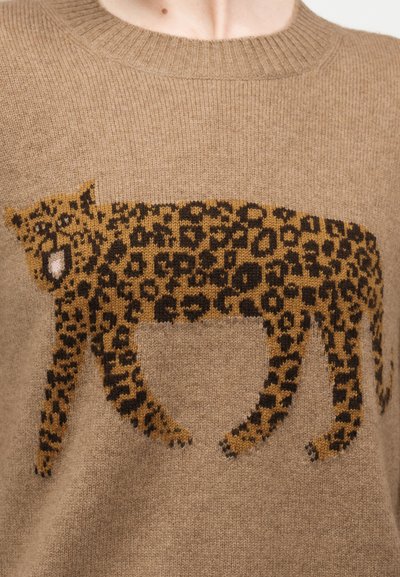 Pull beige en tricot avec un motif détaillé de léopard en marron et noir sur la poitrine.