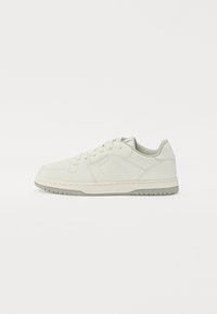 White leather sneaker with a smooth texture, rounded toe, flat laces, and a light grey rubber sole. Subtle embossed detailing on the sides.