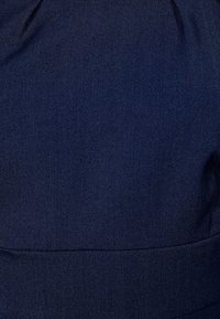 Navy sininen kangas, jossa on sileä pinta, varustettuna kerätyllä yläosalla ja ommellulla sauman alaosalla. Sopii erilaisiin käyttötarkoituksiin.