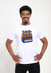 Bílý bavlněný tričko s barevným grafickým motivem pěti lahví sodovky v modré krabici s nápisem "PEPSI." Krátké rukávy a design s kulatým výstřihem.