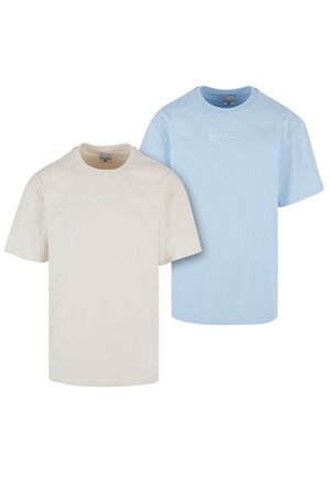 Två kortärmade T-shirts: en i beige och en i ljusblå, båda gjorda av bomull med rund halsringning och en liten vit logotyp.