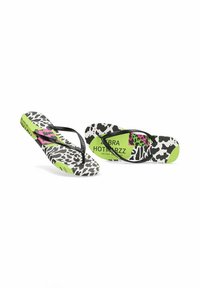 Chanclas con tiras negras, que presentan una plantilla de estampado animal en blanco y negro, detalles en verde y un diseño en rosa con la marca.