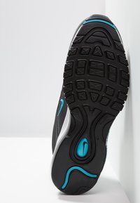 Schwarze Sportledersohle mit strukturiertem Muster, hellblauen Akzenten und geschwungenem Design. Das Material wirkt gummiartig mit Rillen für bessere Traktion.