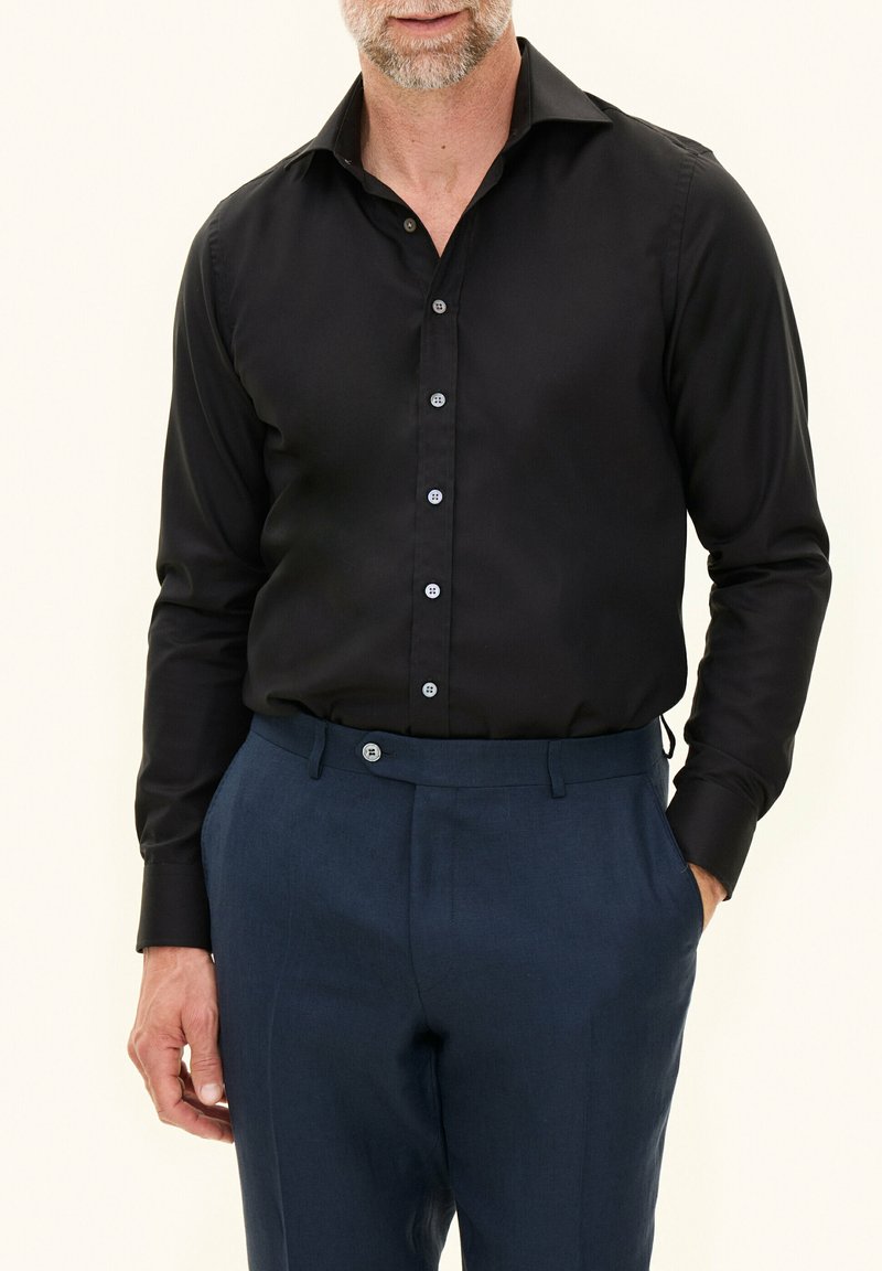 Zwarte lange mouwen shirt met een slim-fit ontwerp, voorzien van een gespreide kraag en een sluiting met vijf knopen, gecombineerd met formele donkerblauwe broek.