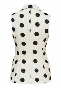 Blazer blanc cintré sans manches à pois noirs, avec col et coutures arrière ajustées.