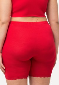 Rode stretchy shorts met een gladde textuur en kantdetails aan de zoom, gedragen met een bijpassende crop top. Het ontwerp is aansluitend.