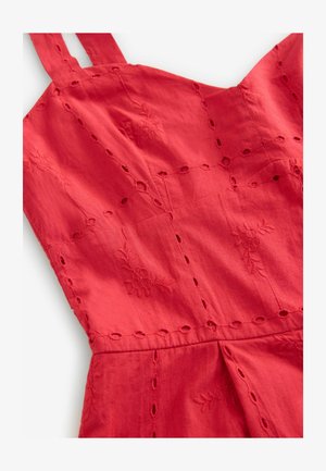 Robe en coton rouge ornée de motifs floraux brodés et de découpes sur le corsage, avec deux bretelles réglables.