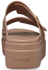 Beige plattform Crocs-sandal med justerbara remmar och texturerad fotbädd, visad från bakvinkel.