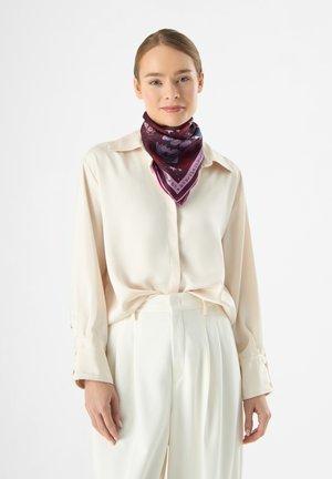 Seidenschal in sattem Burgund mit floralen und textrischen Mustern, kombiniert mit einer cremefarbenen Bluse. Der Schal hat einen kontrastierenden lila Rand.