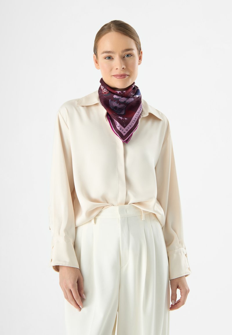 Seidenschal in sattem Burgund mit floralen und textrischen Mustern, kombiniert mit einer cremefarbenen Bluse. Der Schal hat einen kontrastierenden lila Rand.
