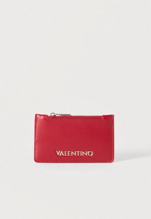 Sarkans ādas karšu turētājs ar rāvējslēdzēja kabatu. Uz priekšpuses zelta krāsas "VALENTINO" logotips. Gluda tekstūra un taisnstūrveida forma.
