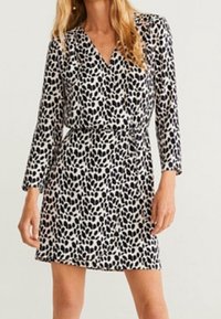 Kurzärmliges Kleid in Creme mit schwarz-grünem Blattmuster, ausgestattet mit einem V-Ausschnitt und einer taillierten Taille für eine figurbetonte Silhouette.