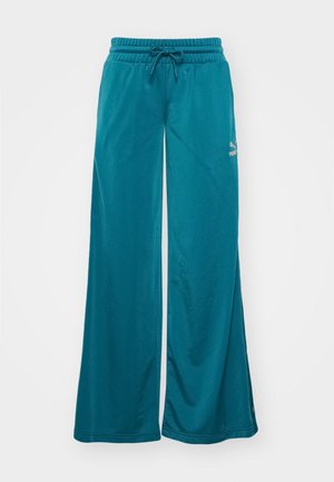 Teal videbuks med elastisk linning, snøre detalj, og en liten logo på venstre side. Smooth overflate.
