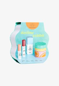 Drunk Elephant daytime exhibit skincare set with four colorful bottles and jars on turquoise background, labeled as morning kit.