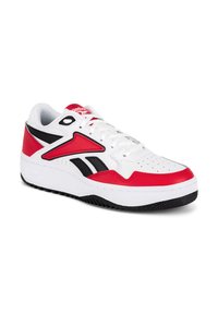 Biele, červené a čierne športové tenisky s šnúrkami, prešitou detailnou úpravou, perforovanou špičkou a hrubou bielou podrážkou s čiernym dezénom.