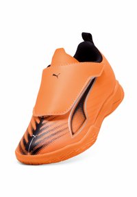 Kirkas oranssi Puma-tenniskenkä mustalla liekkikuvioinnilla, tarranauha suljenta, ja teksturoitu pohja, kulmassa oikealla valkoista taustaa vasten.