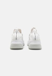 Weiße Sneaker mit einem strukturierten Mesh-Obermaterial, dicker Gummisohle und auffälliger grauer Markenkennzeichnung an der Ferse. Das Design betont Komfort und Unterstützung.