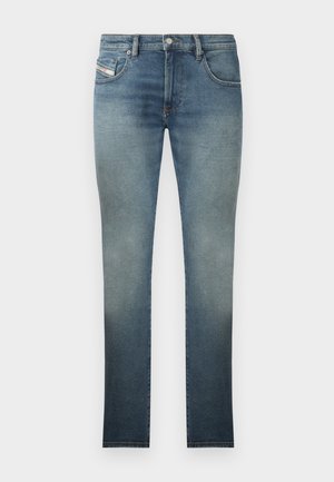 Slim-fit jeans in a faded blue wash, featuring a five-pocket design, metal button closure, and contrast stitching. Slightly distressed texture.