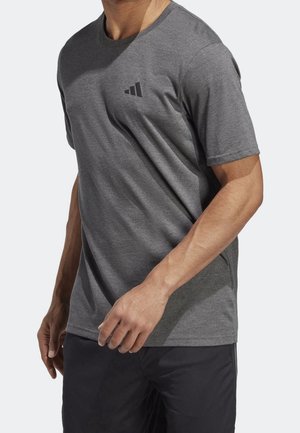Camiseta atlética gris hecha de una tela suave, con cuello redondo y mangas cortas; incluye un pequeño logo negro en el pecho.