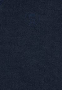 Textil azul marino con una textura suave y lisa; presenta un logotipo sutilmente bordado en el centro sin patrones o adornos adicionales.