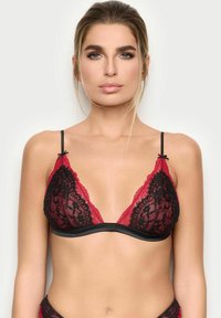 Bralette in pizzo nero e rosso con forma a triangolo, tessuto trasparente e bordatura in raso. Presenta spalline regolabili e fiocchetti decorativi sui coppe.