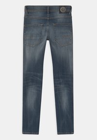 Tmavě modré džíny z denimu, s mírně vybledlým povrchem, designem s pěti kapsami a texturovaným povrchem. Obsahují označenou zadní nášivku.