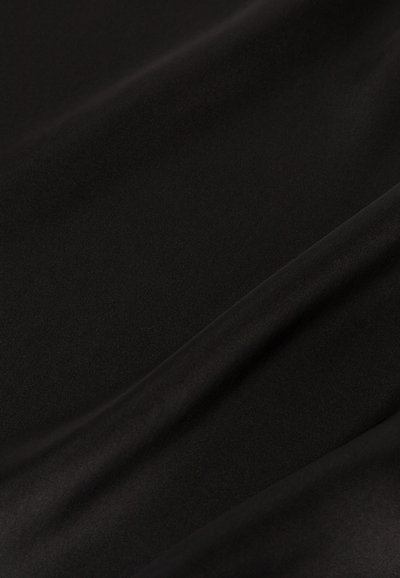 Sima fekete szövet lágy redőkkel és finom textúrával, amelyek lágy árnyékokat és fényeket hoznak létre.