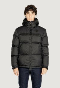 Giubbotto imbottito nero con colletto alto, zip frontale e tasche con zip. Realizzato in nylon lucido con un design trapuntato.