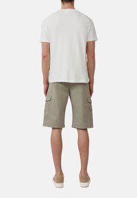Witte t-shirt met korte mouwen en raglanmouwen, gecombineerd met kaki cargoshorts met zijzakken, en lichtgekleurde sneakers.