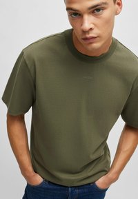 Kortärmad olivgrön T-shirt i strukturerad bomull, med rund halsringning och en diskret präglad 'HUGO'-logotyp på br östet.