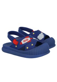 Chanclas de goma azules con diseños de cohetes y nubes, acentos rojos, suela texturizada y correas ajustables. Presenta patrones de estrellas doradas.