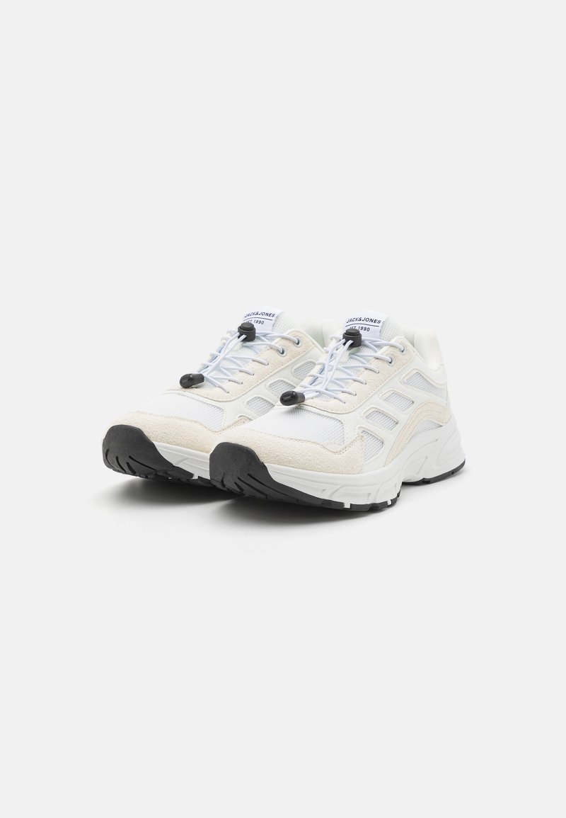 Zapatillas deportivas blancas con una mezcla de materiales de malla y ante, que presentan una suela de goma negra y cordones elásticos con cierre de toggles para un ajuste fácil.