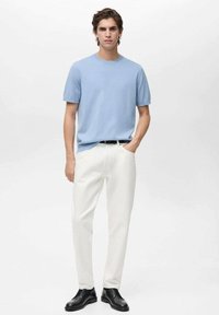 Ljusblå kortärmad t-shirt med rund hals, vita raka byxor och svarta dressade skor. Slät tyg, enkel design, neutrala färger.