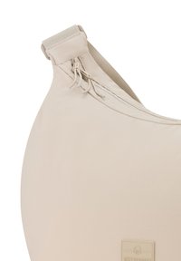 Borsa beige di forma ovale con una texture morbida, dotata di una cerniera nella parte superiore e di una tracolla in tessuto. Presenta una patch con il logo sulla parte anteriore.