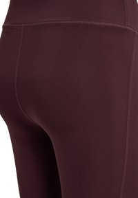 Mørkerøde træningsleggings lavet af strækbart stof, med flade sømme og en glat tekstur samt højtaljet design.