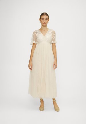 Robe midi couleur crème avec des manches courtes en dentelle transparente, un décolleté en V, et une texture à pois sur l'ensemble de la jupe. Tissu doux et fluide.