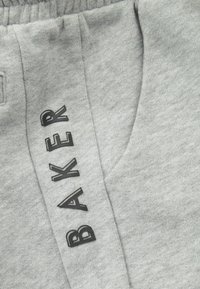 Graue Sweatpants mit weichem Material, versehen mit schwarzem "BAKER"-Text an der Seite. Gestaltet mit einem elastischen Bund und einer Seitentasche.