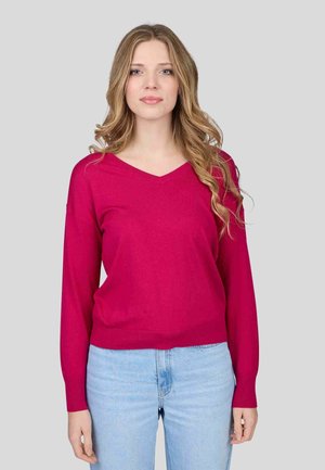 Pull à col en V de couleur rose vif, en tissu tricoté, coupe ample, manches longues, ourlet côtelé, associé à un jean bleu clair.